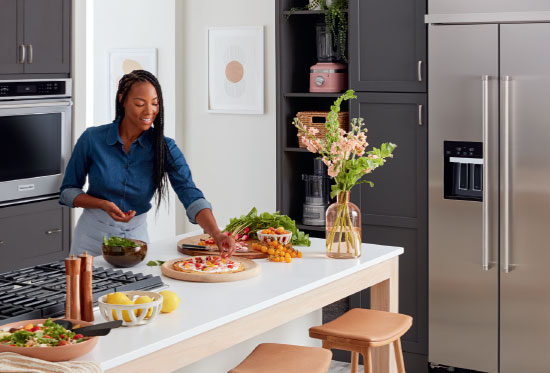 woman cooking in kitchen with Kitchenaid appliances	