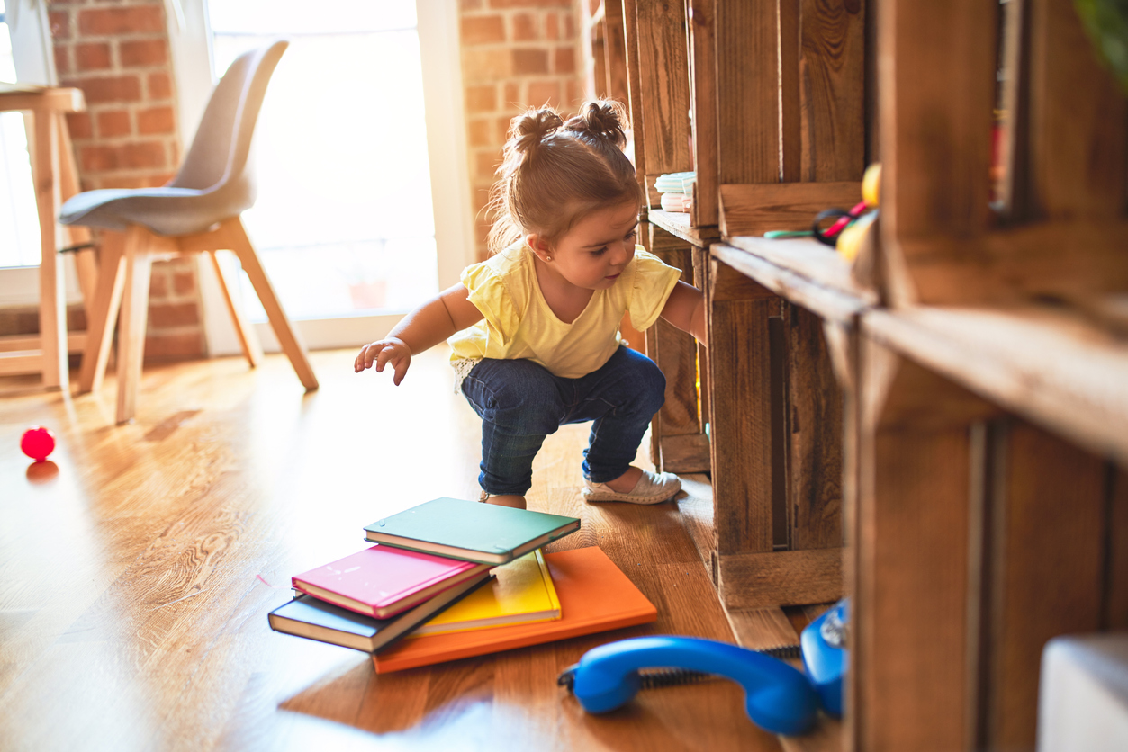 little girl taking books out of bookshelf