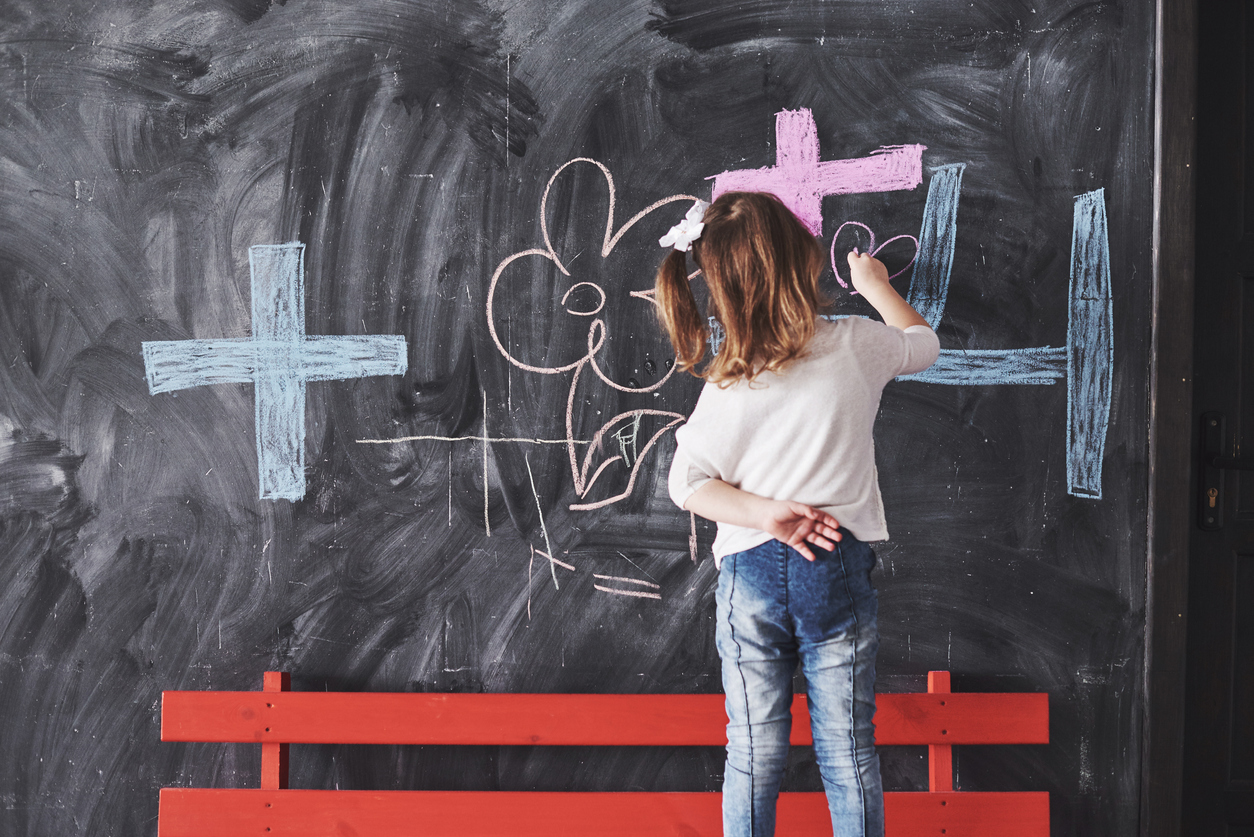 Little girl writing on chalk wall