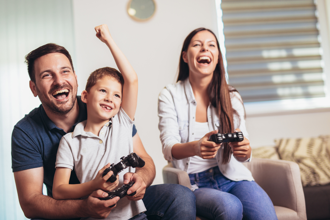 two parents and child playing with game console controls