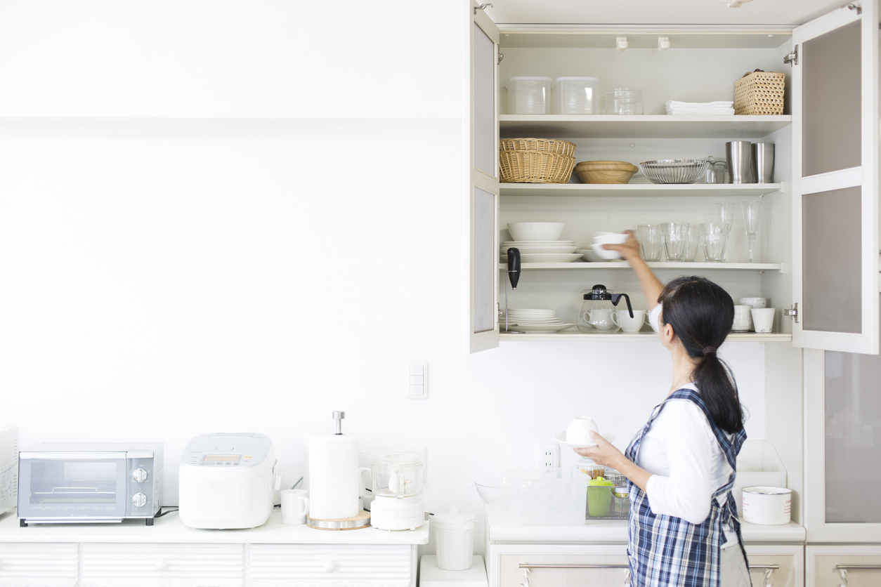woman puts cup away in cupboard